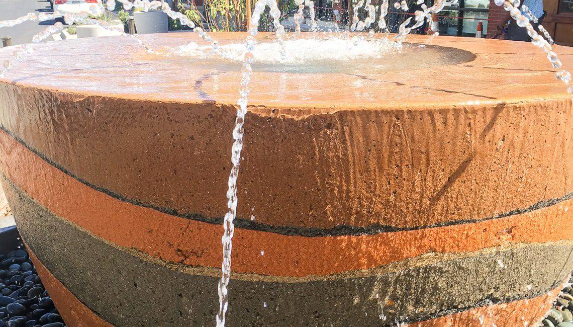 An up close view of the concrete cup shaped water features with nozzles spraying water into its center.