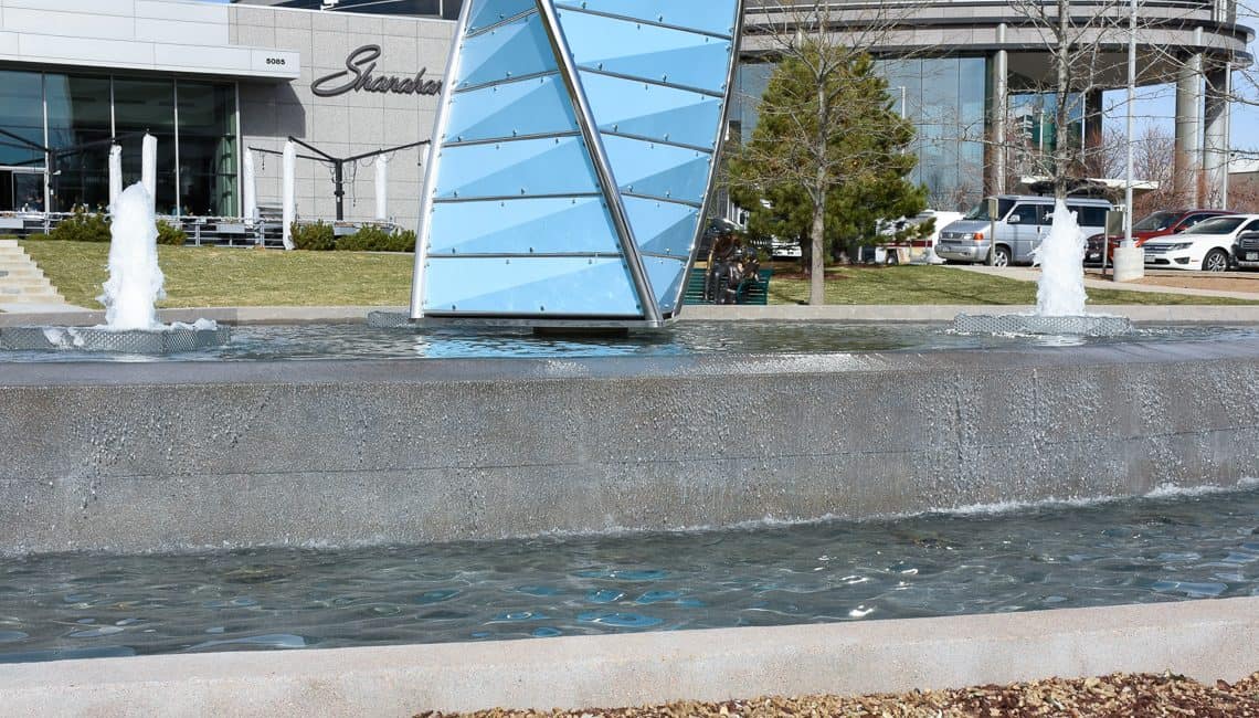 Up-close photo of Denver Tech Center water feature with three geyser nozzles and a large prism centerpiece.