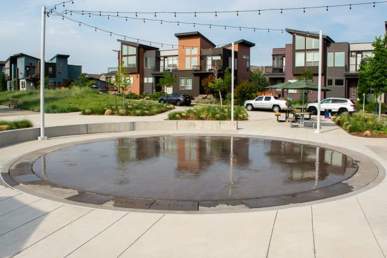 Buffalo Wallow Splash Pad with surrounding planter walls, benches, and lights strung across. Splash Pad done by Colorado Hardscapes.