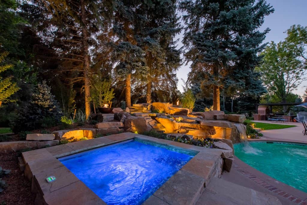 Dream backyard at private residence with RGB lighting in spa and sandstone waterfall.